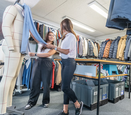 Zwei Mitarbeiterinnen arbeiten mit Stoff an einem Mannequin
